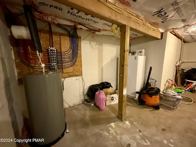 unfinished below grade area featuring water heater and fridge