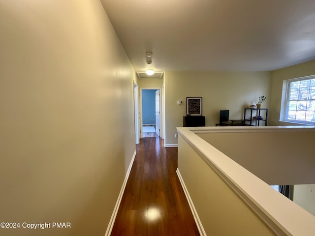 hallway with baseboards, dark wood finished floors, and an upstairs landing