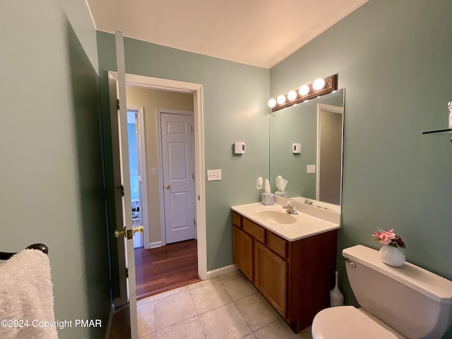 bathroom featuring toilet, tile patterned floors, baseboards, and vanity