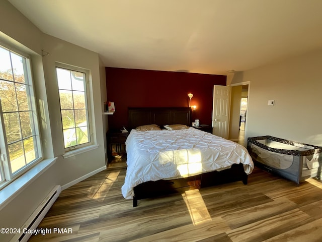 bedroom featuring a baseboard radiator, baseboards, and wood finished floors