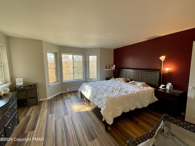 bedroom with baseboard heating, wood finished floors, and baseboards