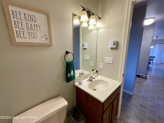 half bath with vanity, toilet, and an inviting chandelier