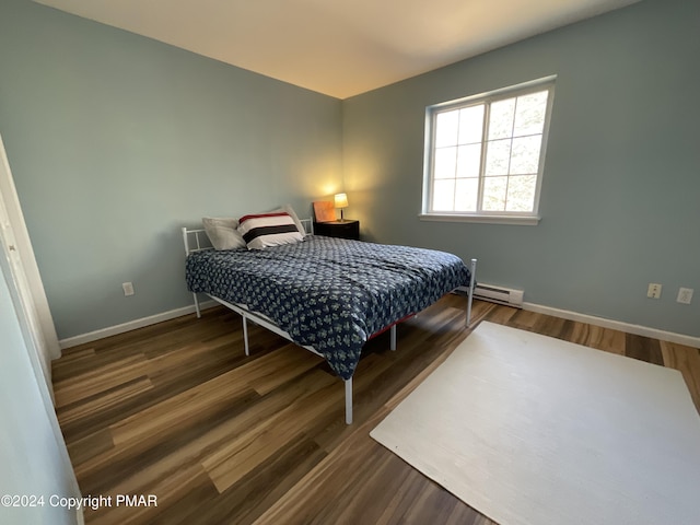 bedroom featuring a baseboard heating unit, baseboards, and wood finished floors