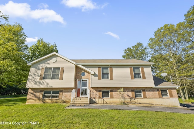 split foyer home with entry steps, a front lawn, and brick siding