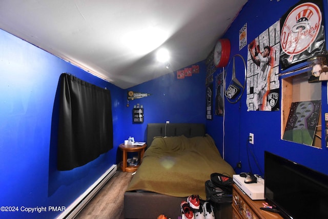 unfurnished bedroom featuring baseboard heating and wood finished floors