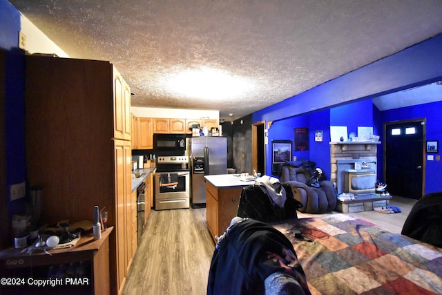 bedroom with light wood finished floors, stainless steel refrigerator with ice dispenser, and a textured ceiling