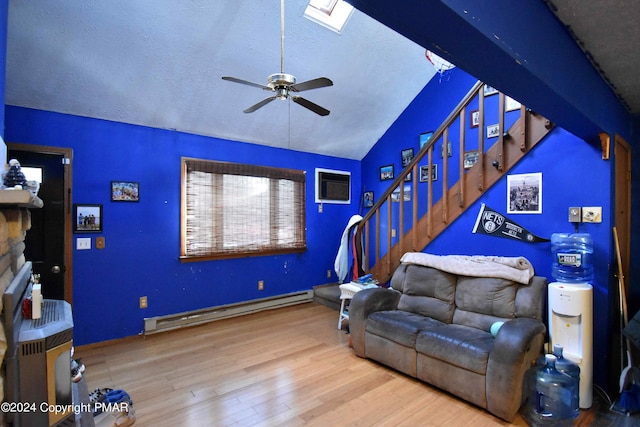 living room with lofted ceiling with skylight, a baseboard radiator, wood finished floors, stairs, and a textured ceiling