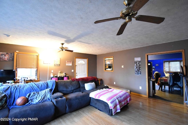 living room with a textured ceiling, ceiling fan, wood finished floors, and baseboards