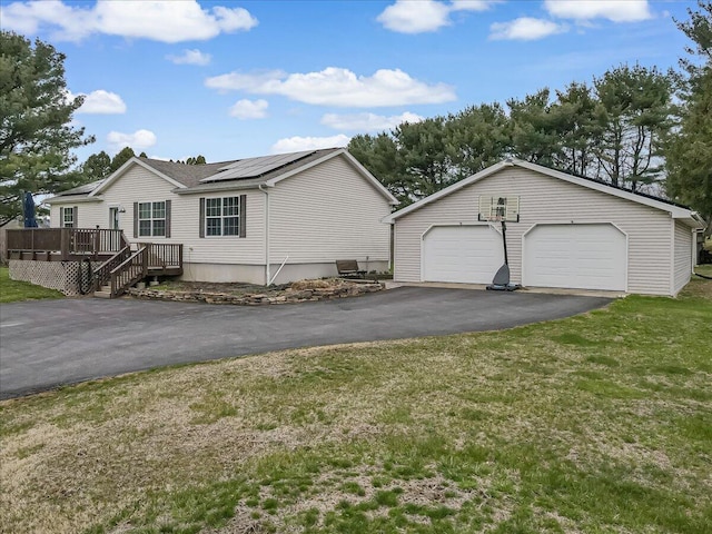 3954 Cedar Dr, Walnutport, PA 18088 - view of front facade featuring a deck, roof mounted solar panels, a detached garage, a front lawn, and an outdoor structure