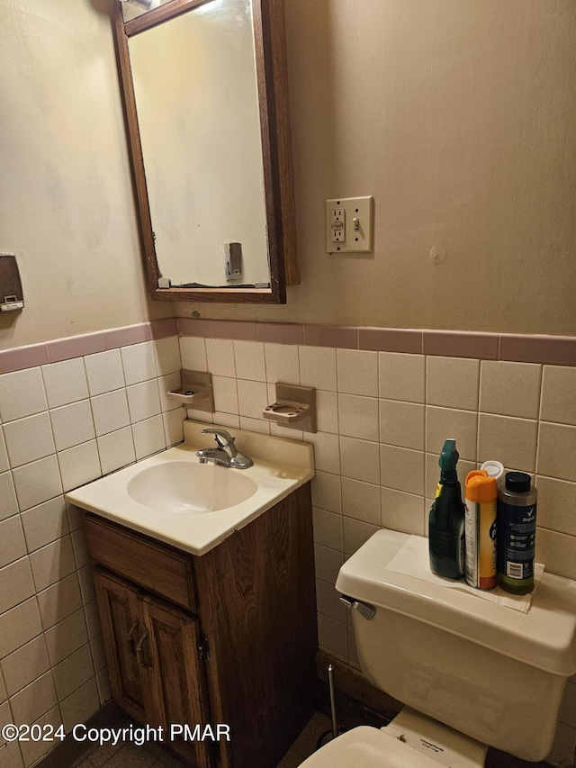 bathroom featuring vanity, tile walls, toilet, and a wainscoted wall