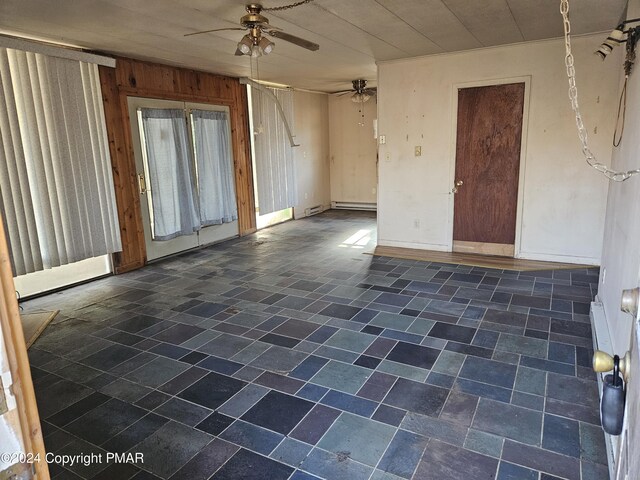 unfurnished room featuring a ceiling fan, baseboards, and wood walls