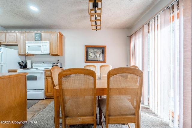 kitchen with a textured ceiling, light countertops, white appliances, and light brown cabinets