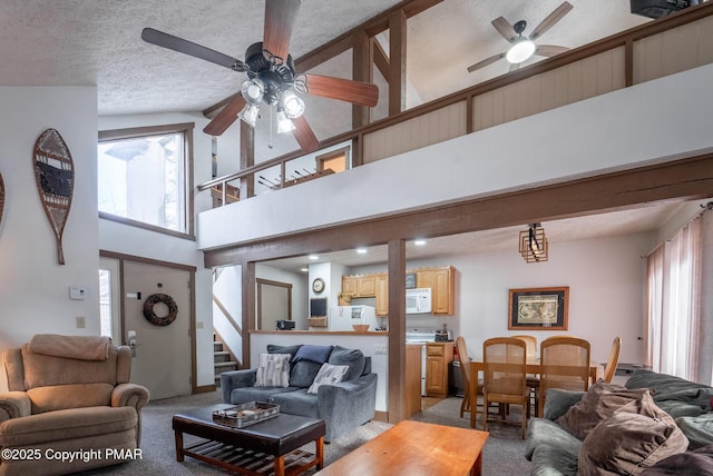 living area featuring a ceiling fan, light colored carpet, stairway, a high ceiling, and a textured ceiling