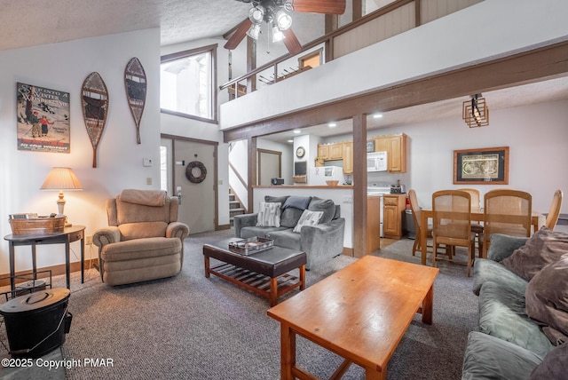 living room featuring high vaulted ceiling, light colored carpet, a ceiling fan, baseboards, and stairs