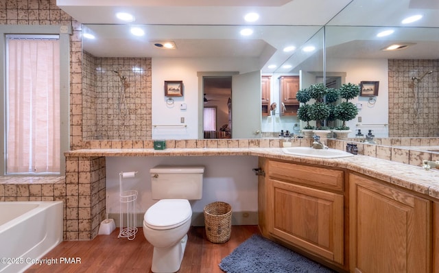 bathroom with a washtub, vanity, wood finished floors, and toilet