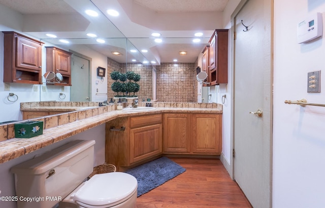 kitchen with a peninsula, light countertops, light wood-style floors, a sink, and recessed lighting