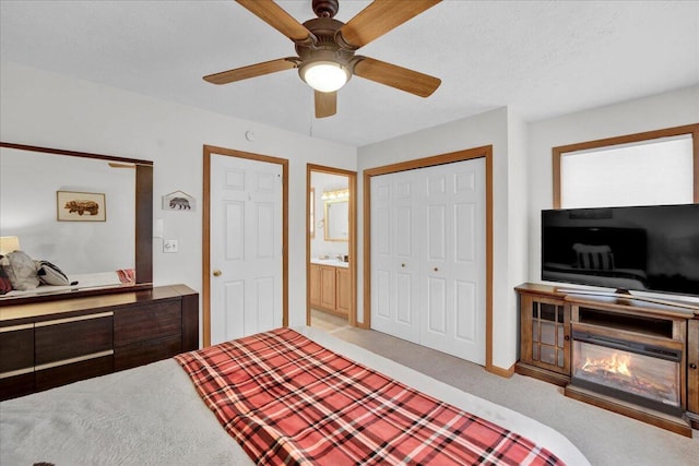 bedroom featuring carpet floors, a closet, a glass covered fireplace, and a ceiling fan