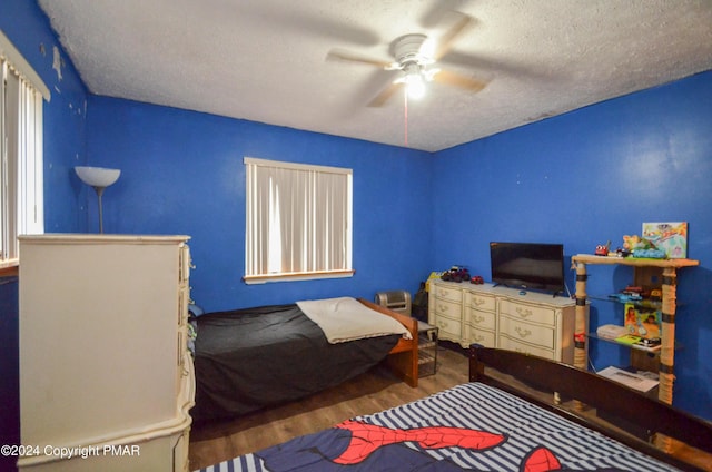 bedroom with ceiling fan, a textured ceiling, and wood finished floors