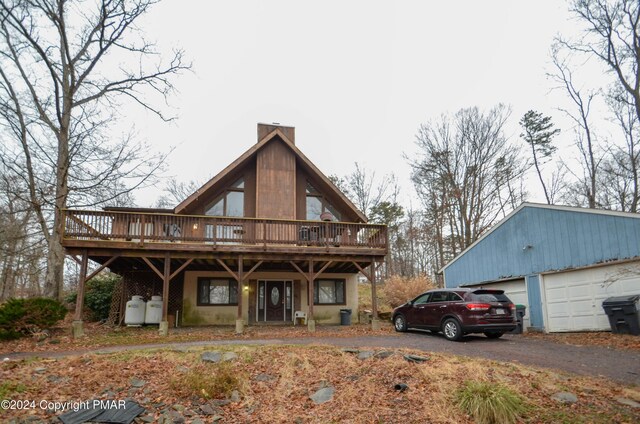 rear view of property with a wooden deck and a garage