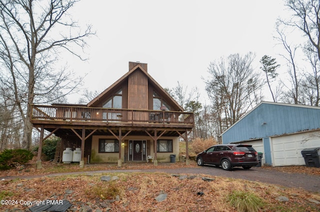 view of front of house with an outbuilding, a chimney, aphalt driveway, and a deck