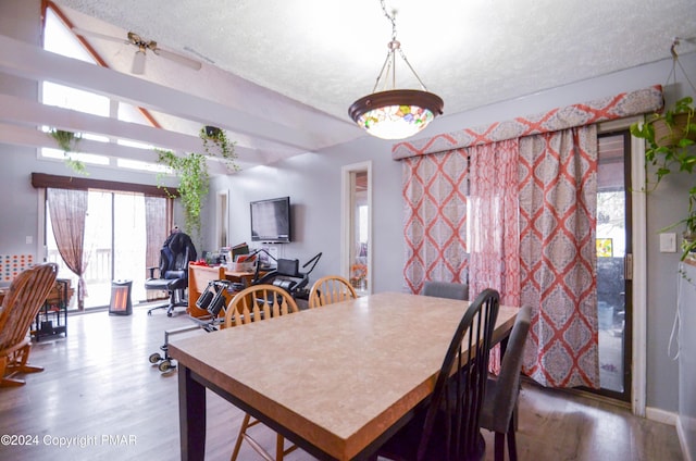 dining area featuring lofted ceiling, a textured ceiling, wood finished floors, and a ceiling fan