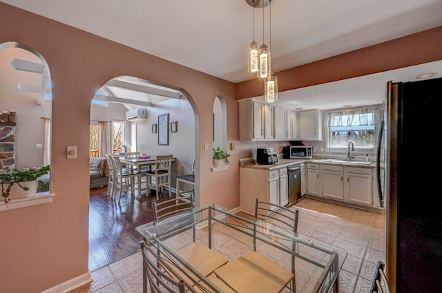 kitchen with a wall unit AC, appliances with stainless steel finishes, arched walkways, a sink, and light countertops