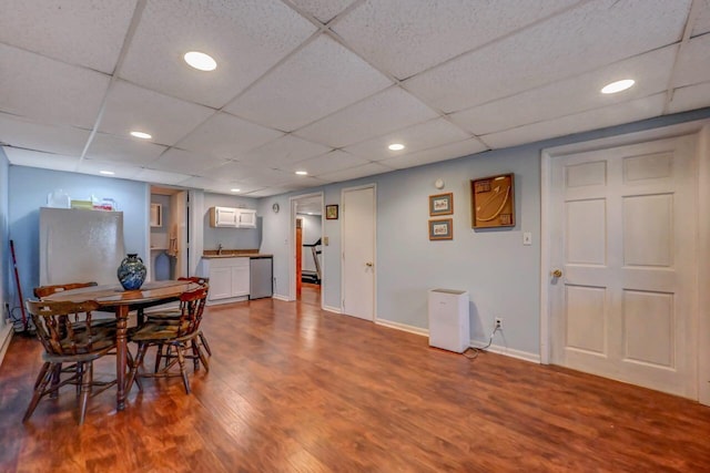 dining space with baseboards, a drop ceiling, recessed lighting, and dark wood-type flooring