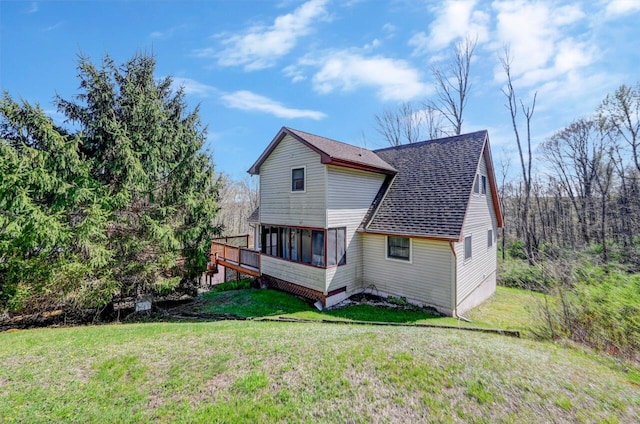 rear view of house with roof with shingles, a lawn, and a deck
