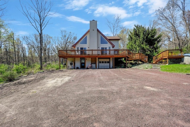 back of house featuring a garage, dirt driveway, a wooden deck, and a chimney