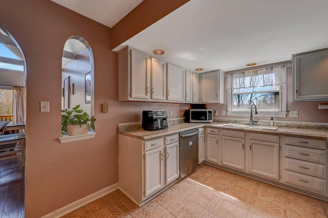 kitchen with a sink, appliances with stainless steel finishes, light countertops, and a healthy amount of sunlight
