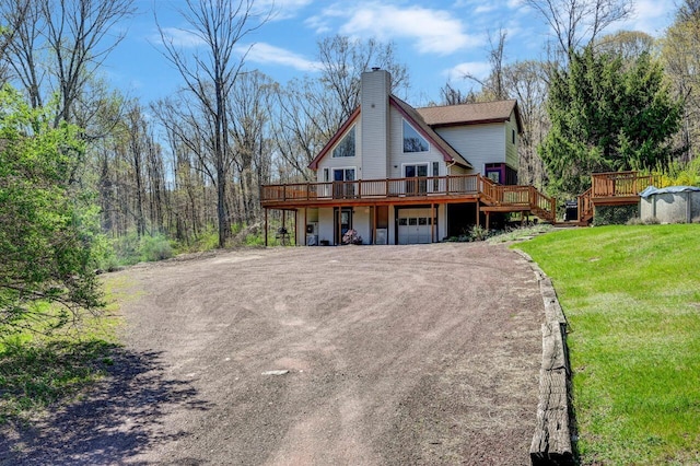 back of house with a garage, a wooden deck, a chimney, and driveway