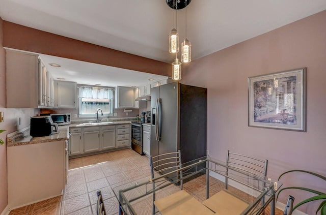 kitchen featuring decorative light fixtures, appliances with stainless steel finishes, a sink, light countertops, and under cabinet range hood