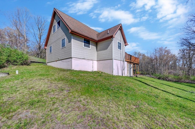view of property exterior with roof with shingles and a yard