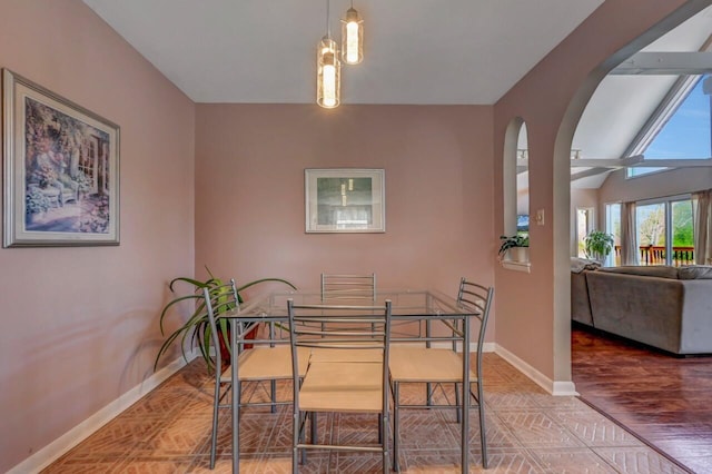 dining area with arched walkways, baseboards, vaulted ceiling, and wood finished floors
