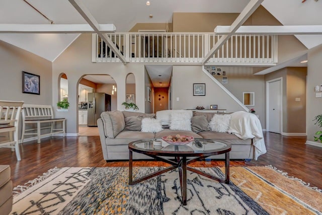 living room featuring baseboards, arched walkways, wood finished floors, and high vaulted ceiling
