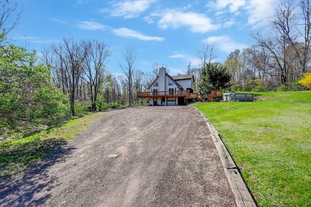 view of front of home with driveway, a chimney, a deck, an outdoor pool, and a front lawn