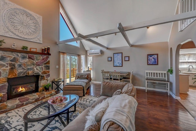 living area with wood finished floors, baseboards, high vaulted ceiling, an AC wall unit, and arched walkways