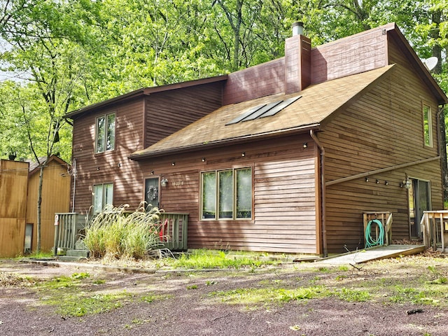 5081 Woodbridge Dr E, Bushkill, PA 18324 - rear view of property with a shingled roof and a chimney