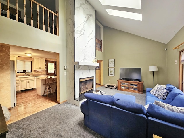 5081 Woodbridge Dr E, Bushkill, PA 18324 - living room with high vaulted ceiling, a skylight, a fireplace, light carpet, and light wood-type flooring