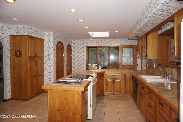 6760 Bear Creek Blvd, Bear Creek Township, PA 18702 - kitchen with light tile patterned floors, a sink, wallpapered walls, a skylight, and tile countertops