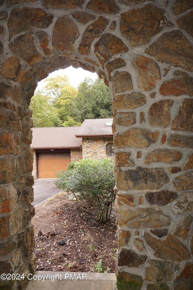 6760 Bear Creek Blvd, Bear Creek Township, PA 18702 - exterior space with stone siding, a shingled roof, a garage, and aphalt driveway