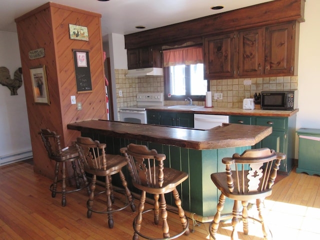 kitchen with light wood-style flooring, under cabinet range hood, a sink, tasteful backsplash, and white appliances