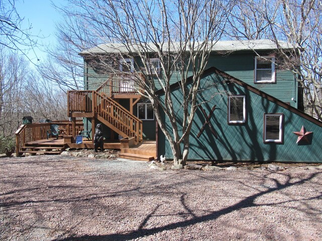 rear view of property featuring stairs and a wooden deck