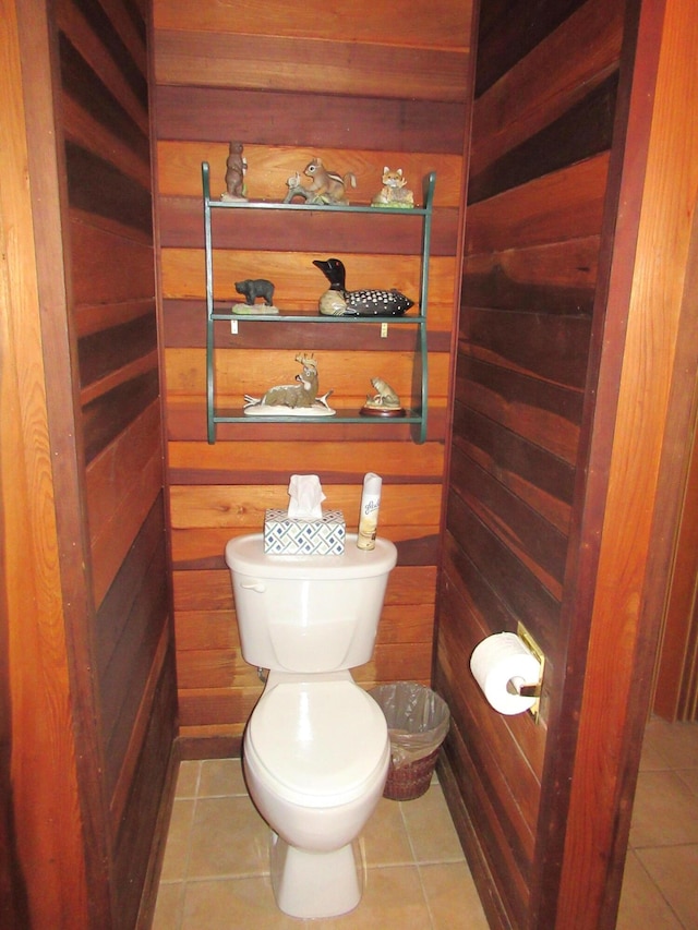 bathroom with tile patterned floors, wooden walls, and toilet