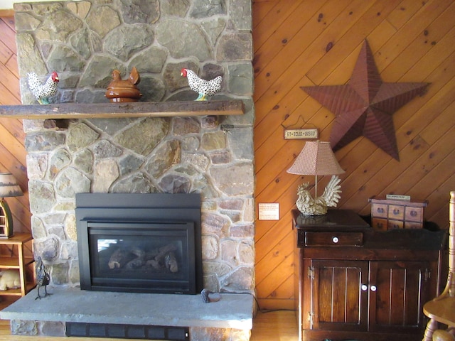 details with a stone fireplace, wood walls, and wood finished floors