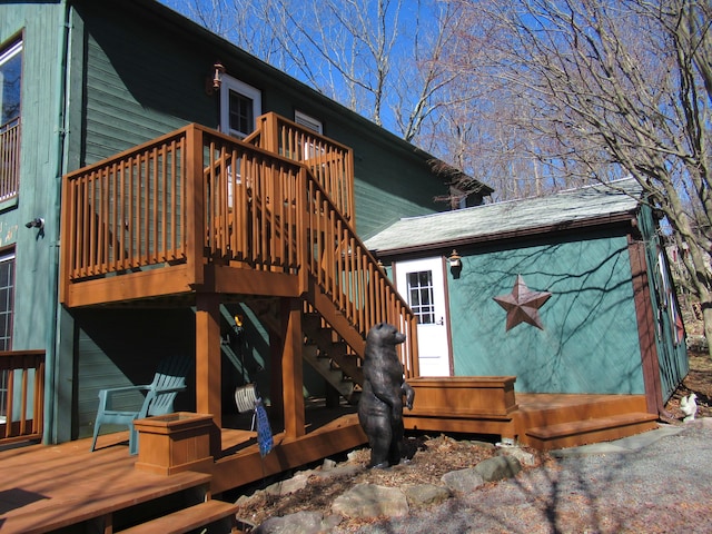 back of property featuring a wooden deck, roof with shingles, and stairs