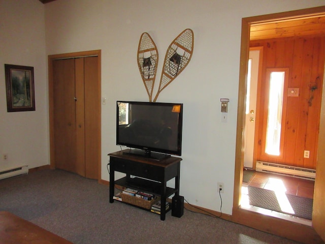 living room with a baseboard heating unit, carpet flooring, baseboards, and wood walls