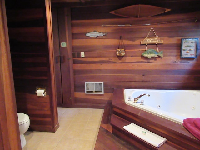 bathroom featuring tile patterned flooring, visible vents, wood walls, toilet, and a tub with jets