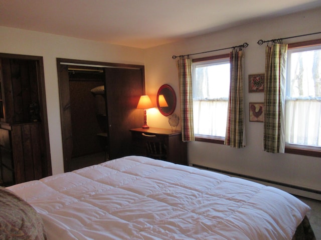 bedroom featuring multiple windows and a baseboard heating unit