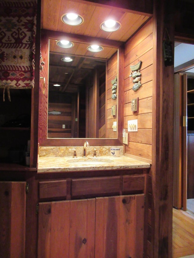 bathroom featuring wooden walls, recessed lighting, wooden ceiling, and vanity